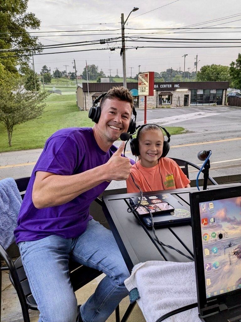 A man and a little girl are sitting at a table with headphones on.