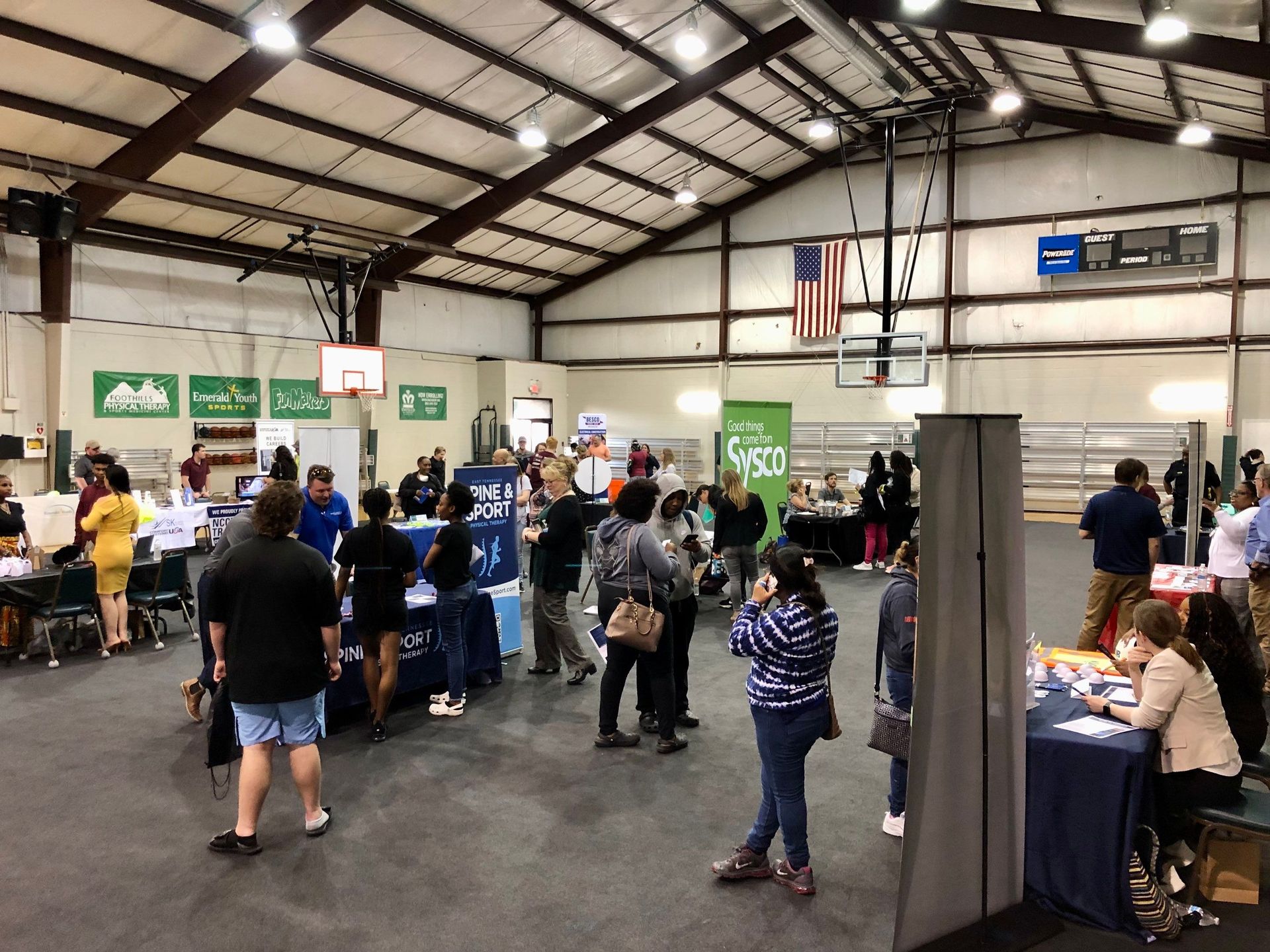 A group of people are standing around tables in a large room.