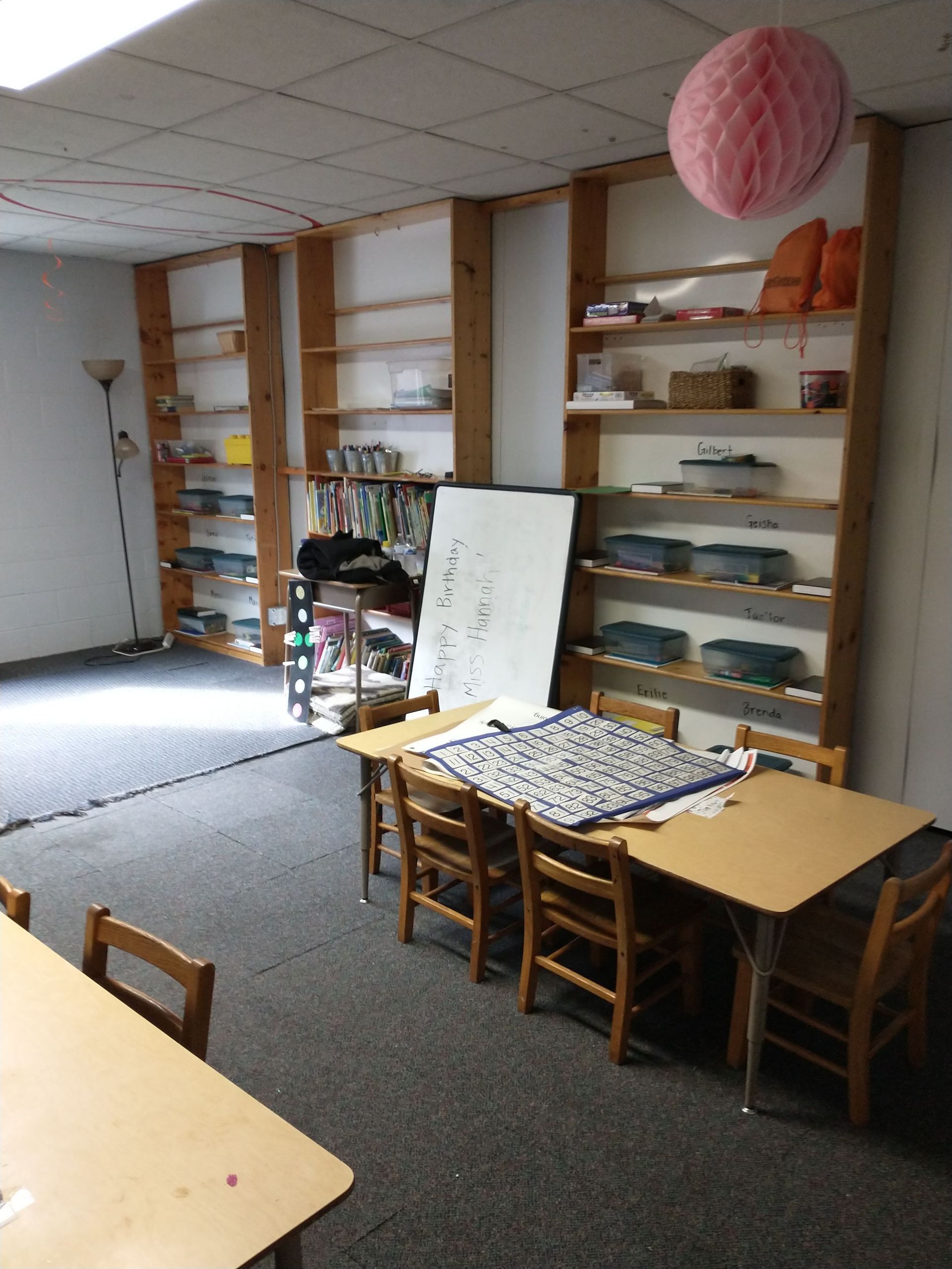 A room with tables and chairs and a pink ball hanging from the ceiling