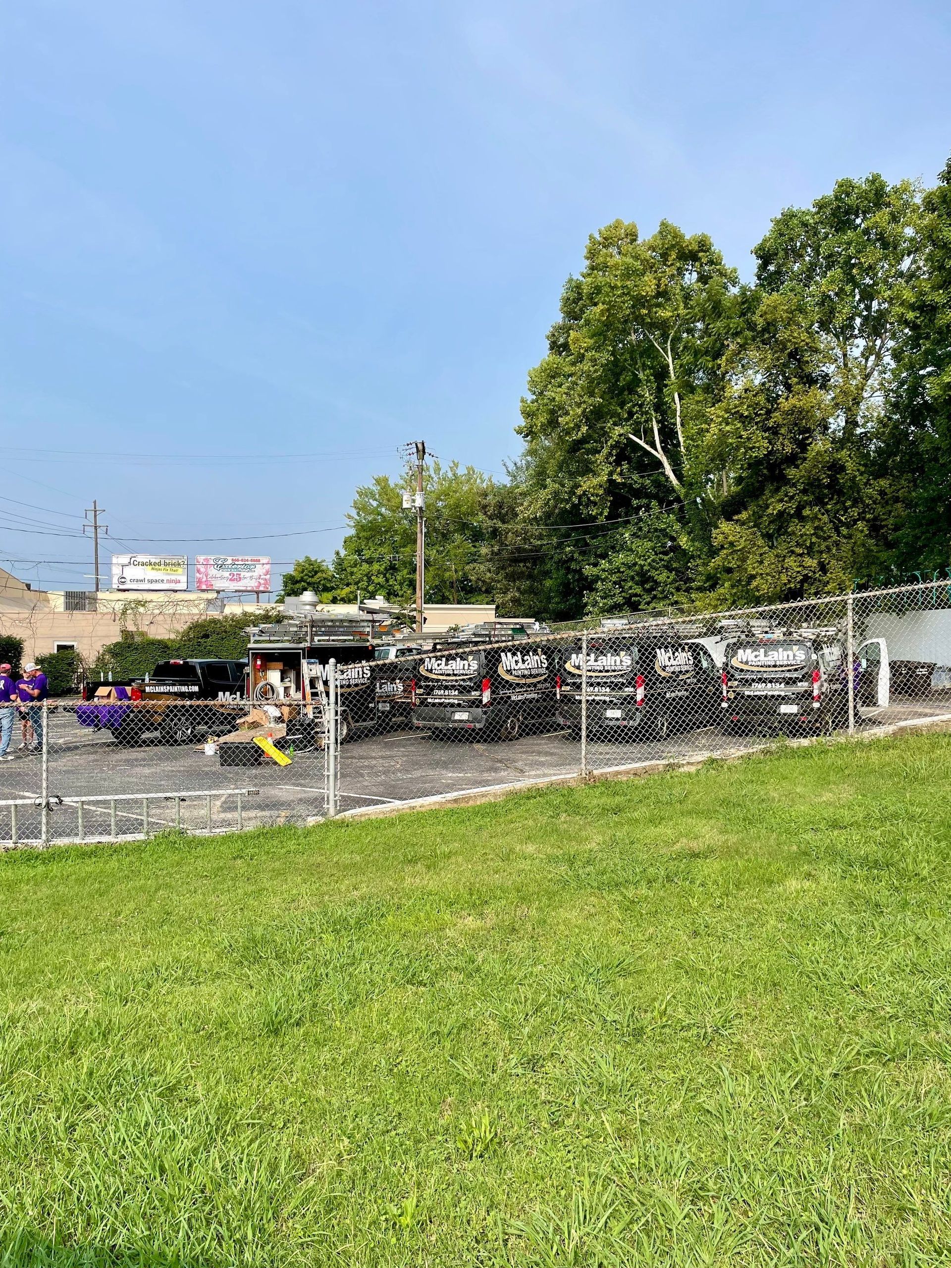 A lot of cars are parked in a lot behind a fence.