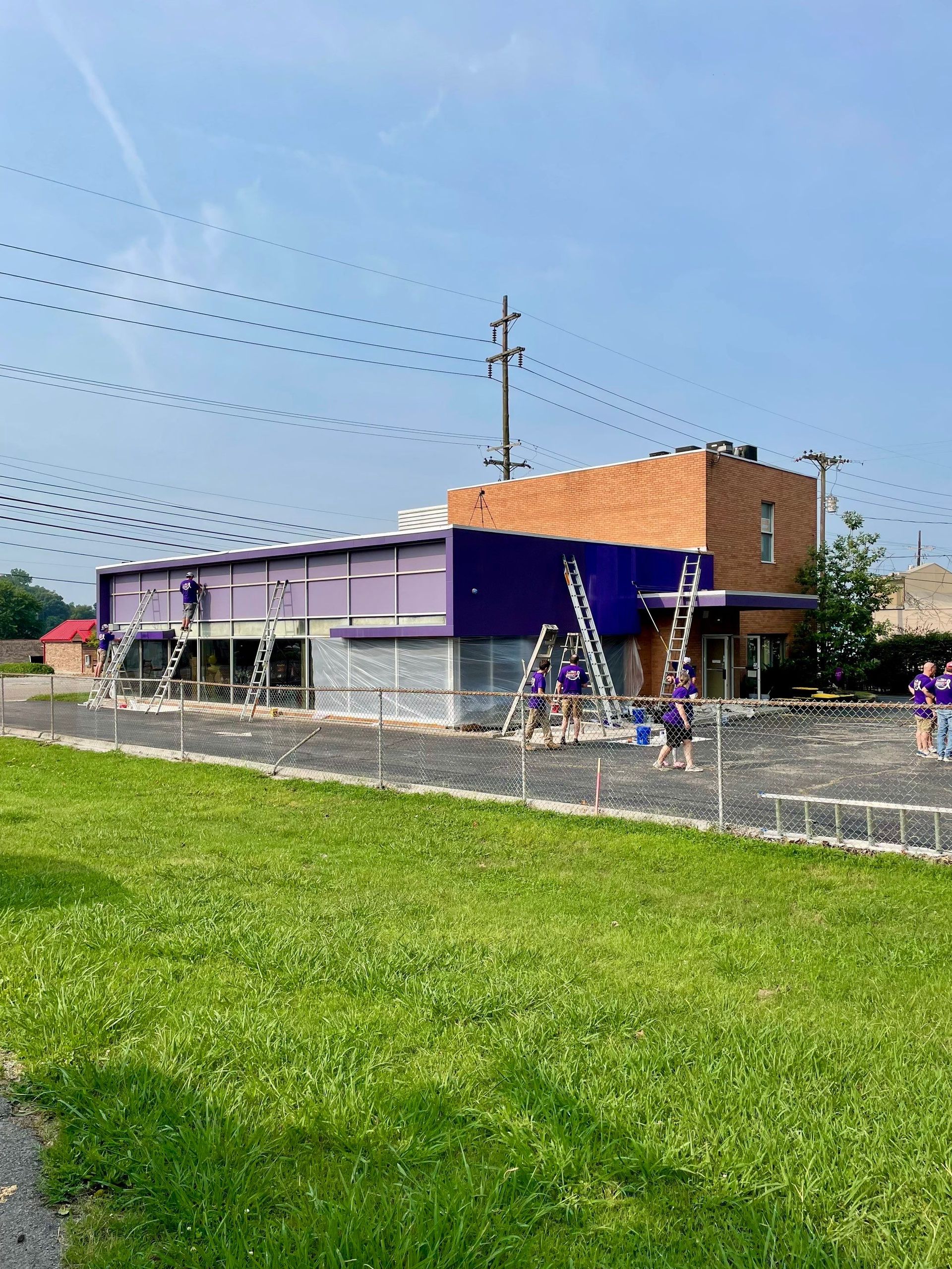 A group of people are painting a purple building.
