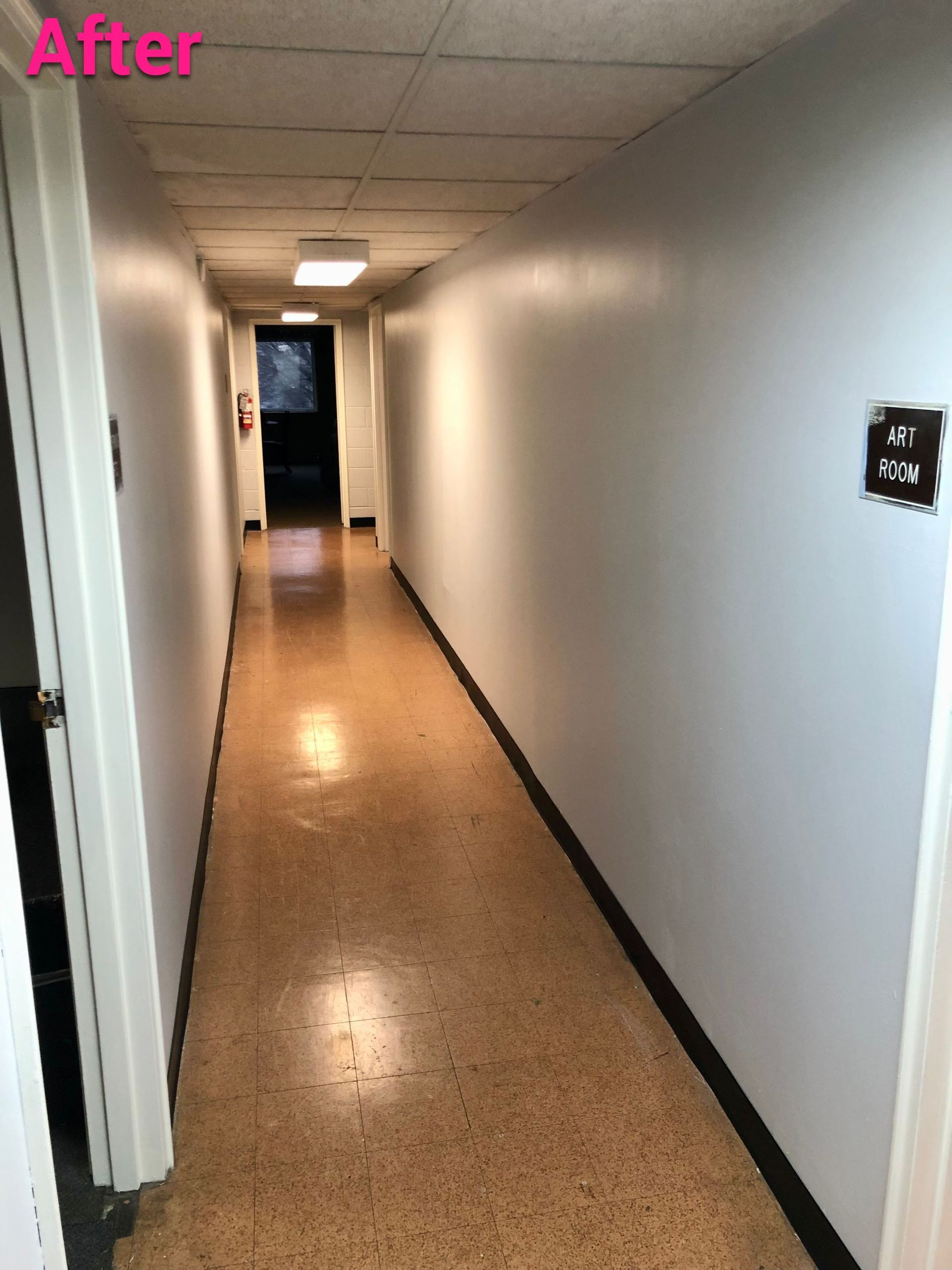 A long hallway with white walls and a pink sign that says after