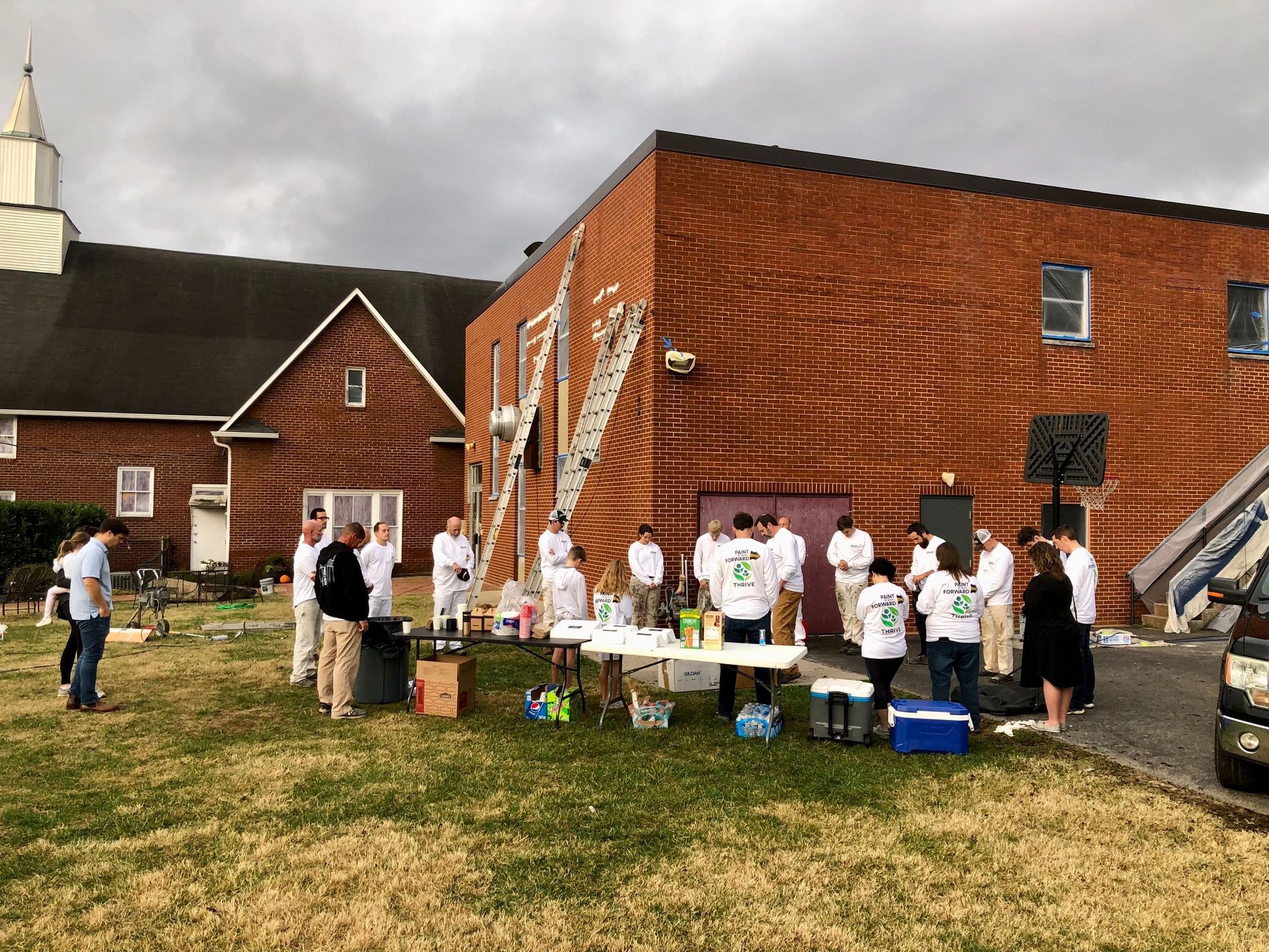 A group of people are standing in front of a brick building.