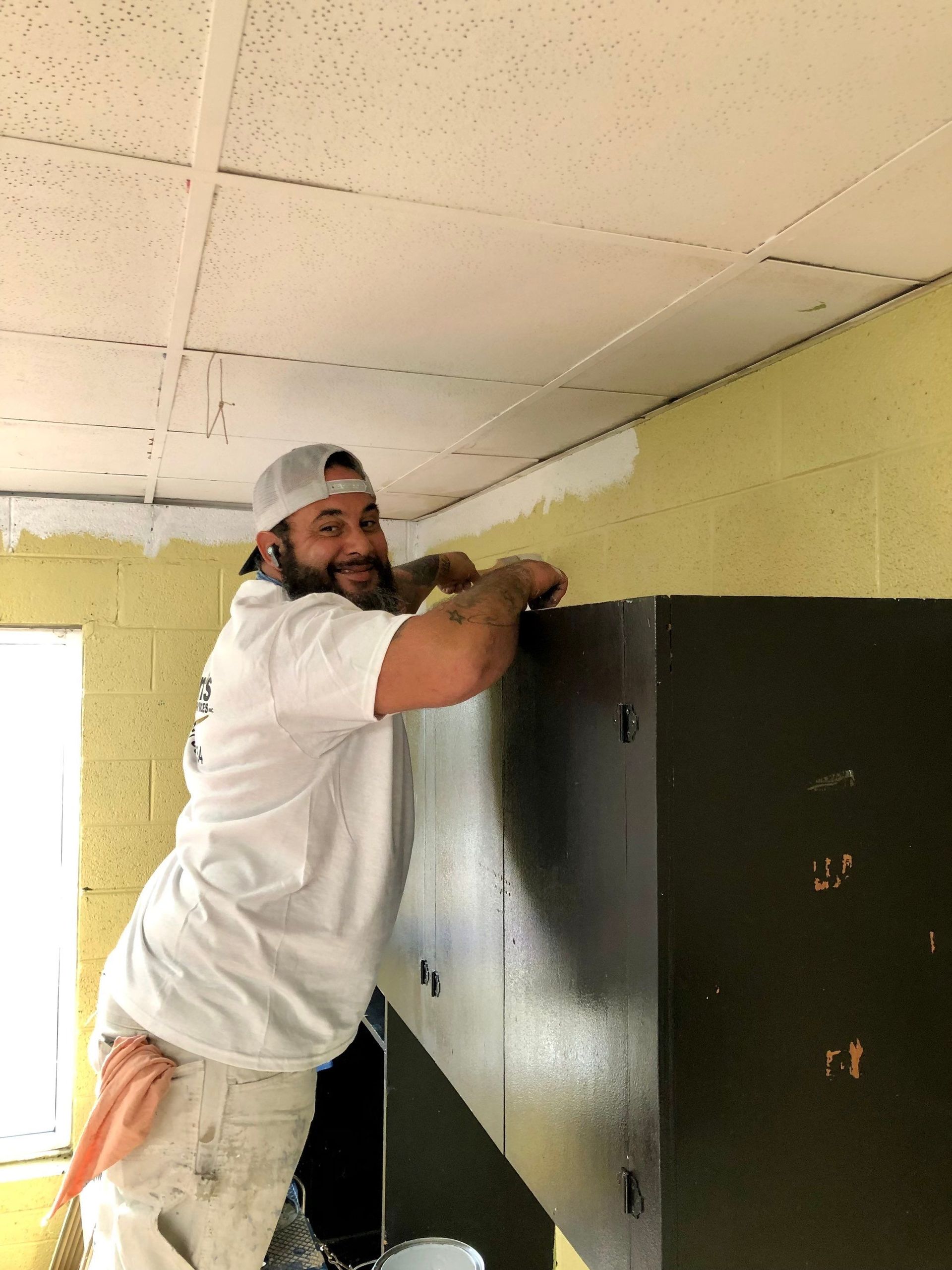 A man in a white shirt is painting a wall.