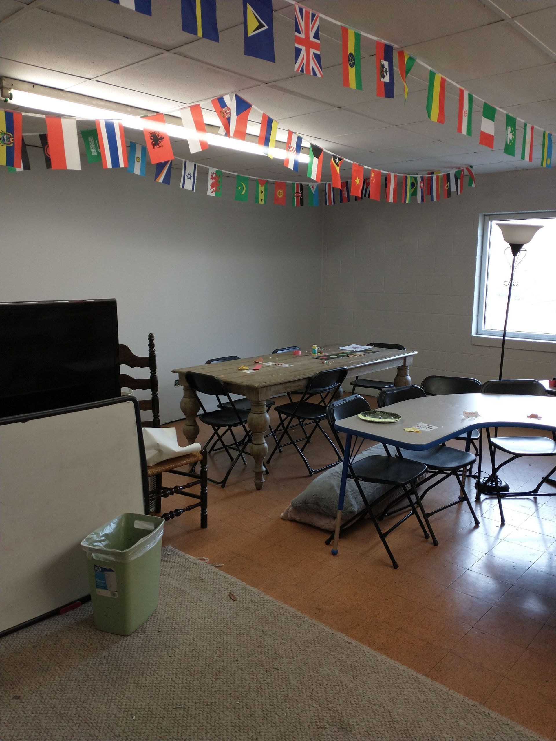 A room with tables and chairs and flags hanging from the ceiling