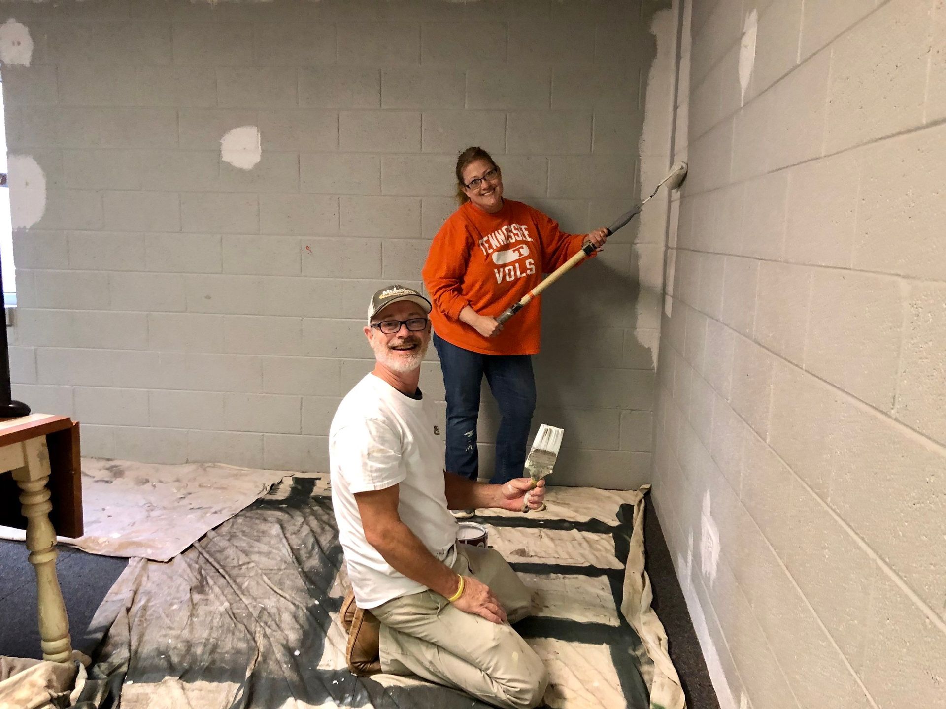 A man and a woman are painting a wall together.