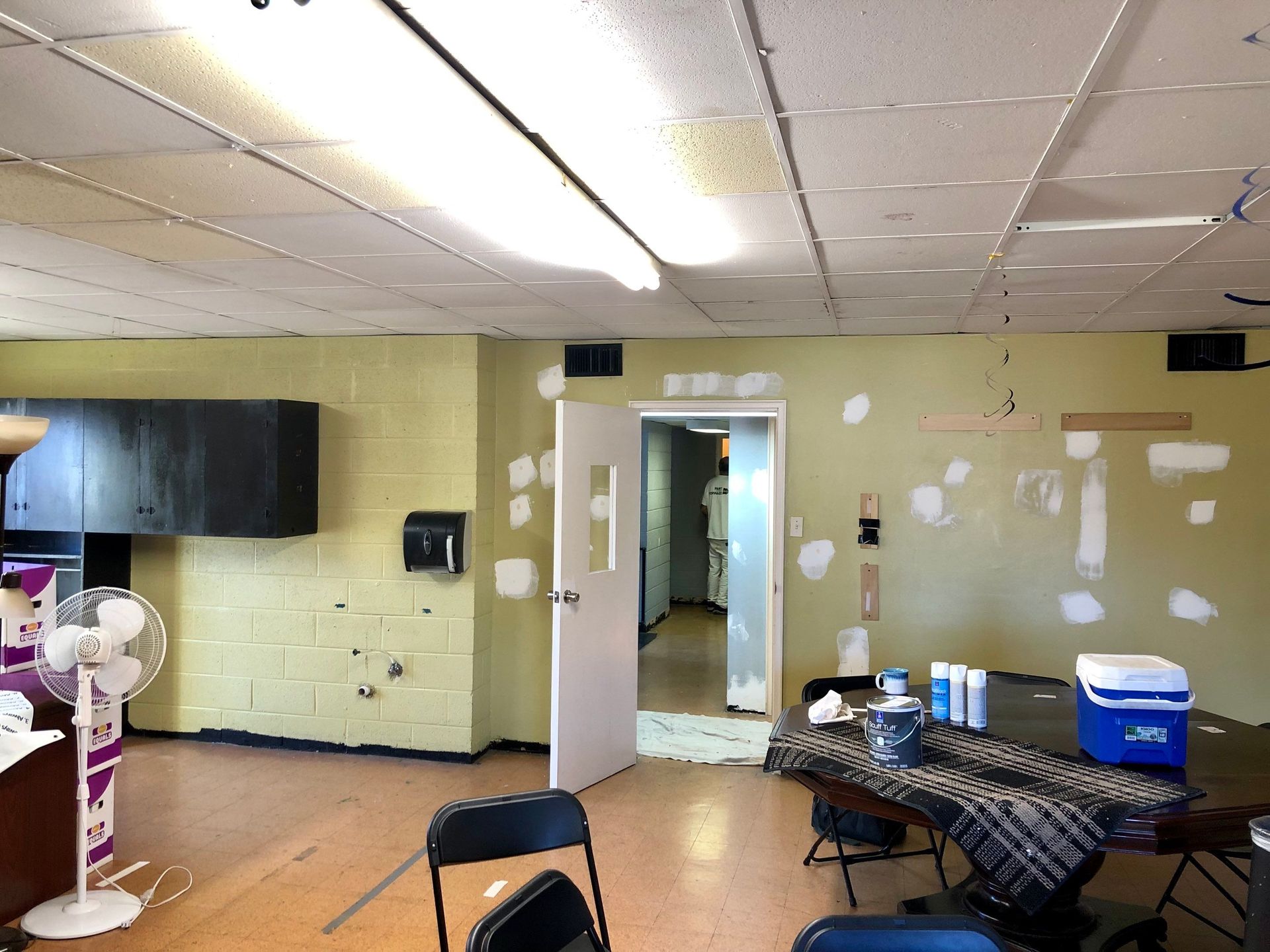An empty room with a table and chairs and a blue cooler