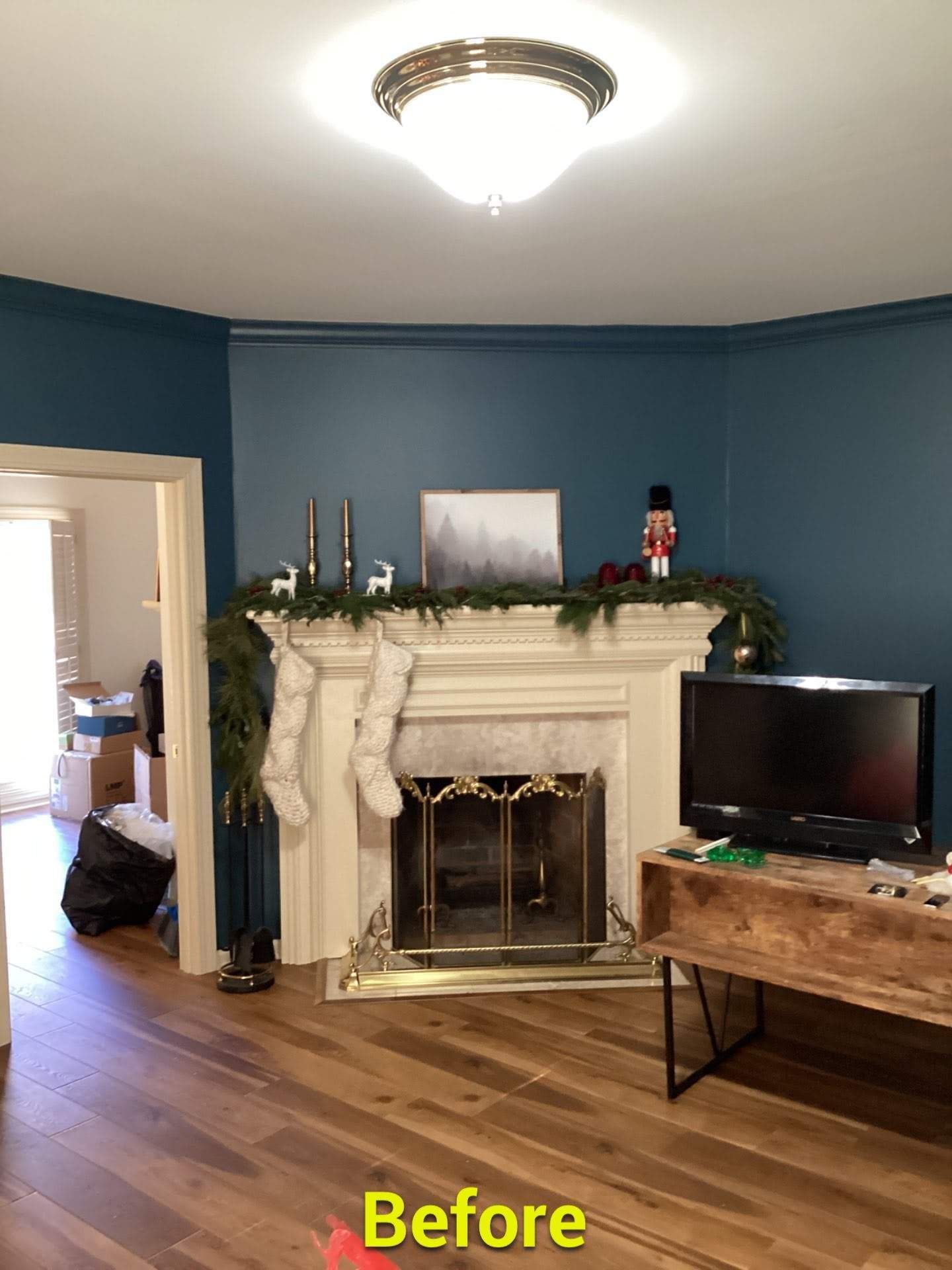 A living room with blue walls and a fireplace decorated for christmas
