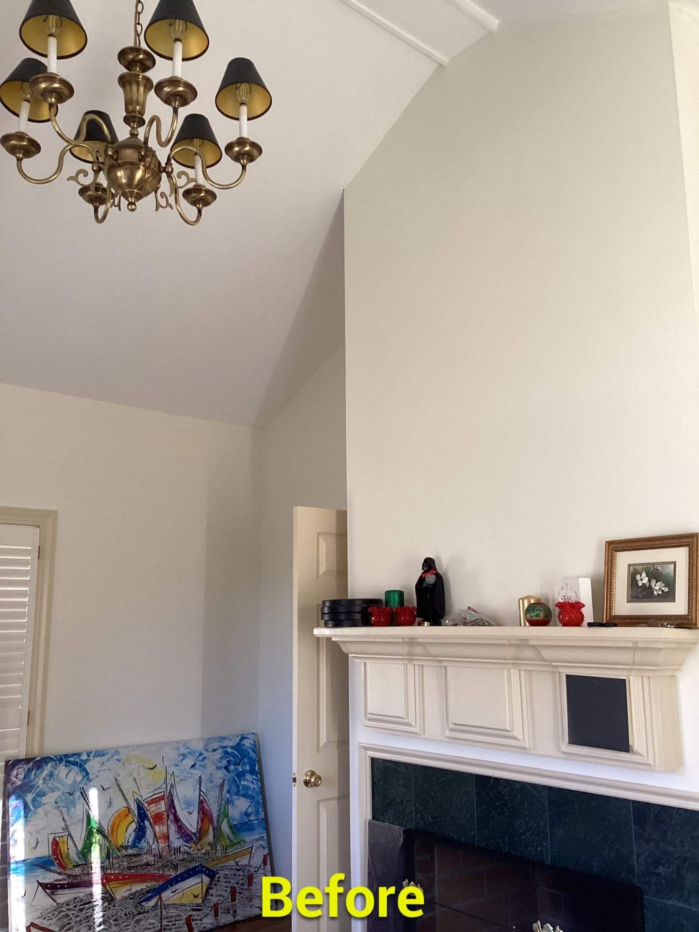 A before picture of a living room with a fireplace and a chandelier