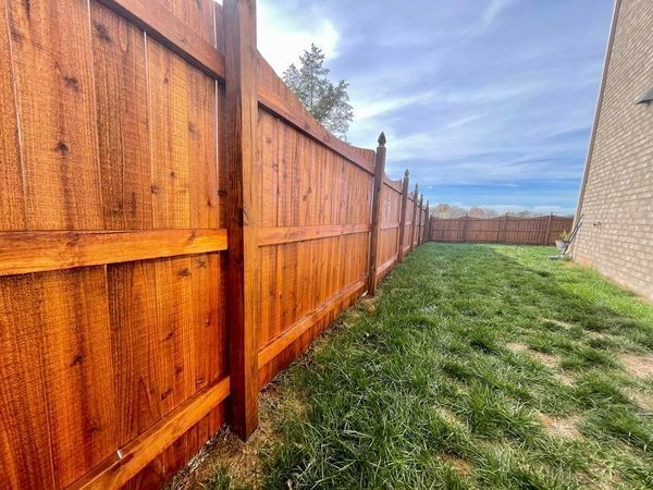 A wooden fence surrounds a lush green yard.