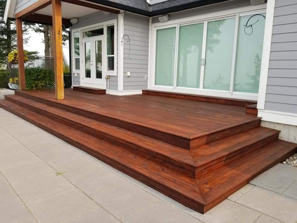 A house with a wooden deck and stairs in front of it.