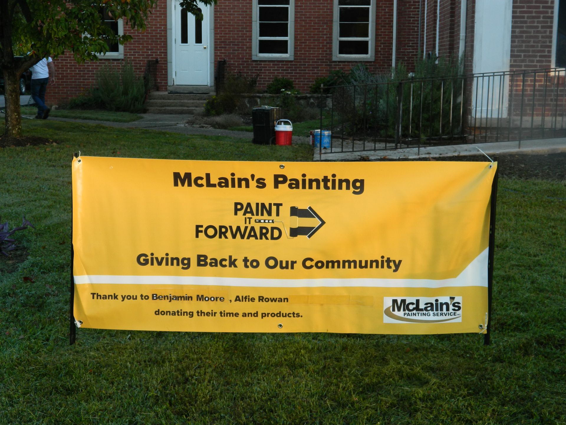 A yellow sign that says mclain 's painting paint forward giving back to our community