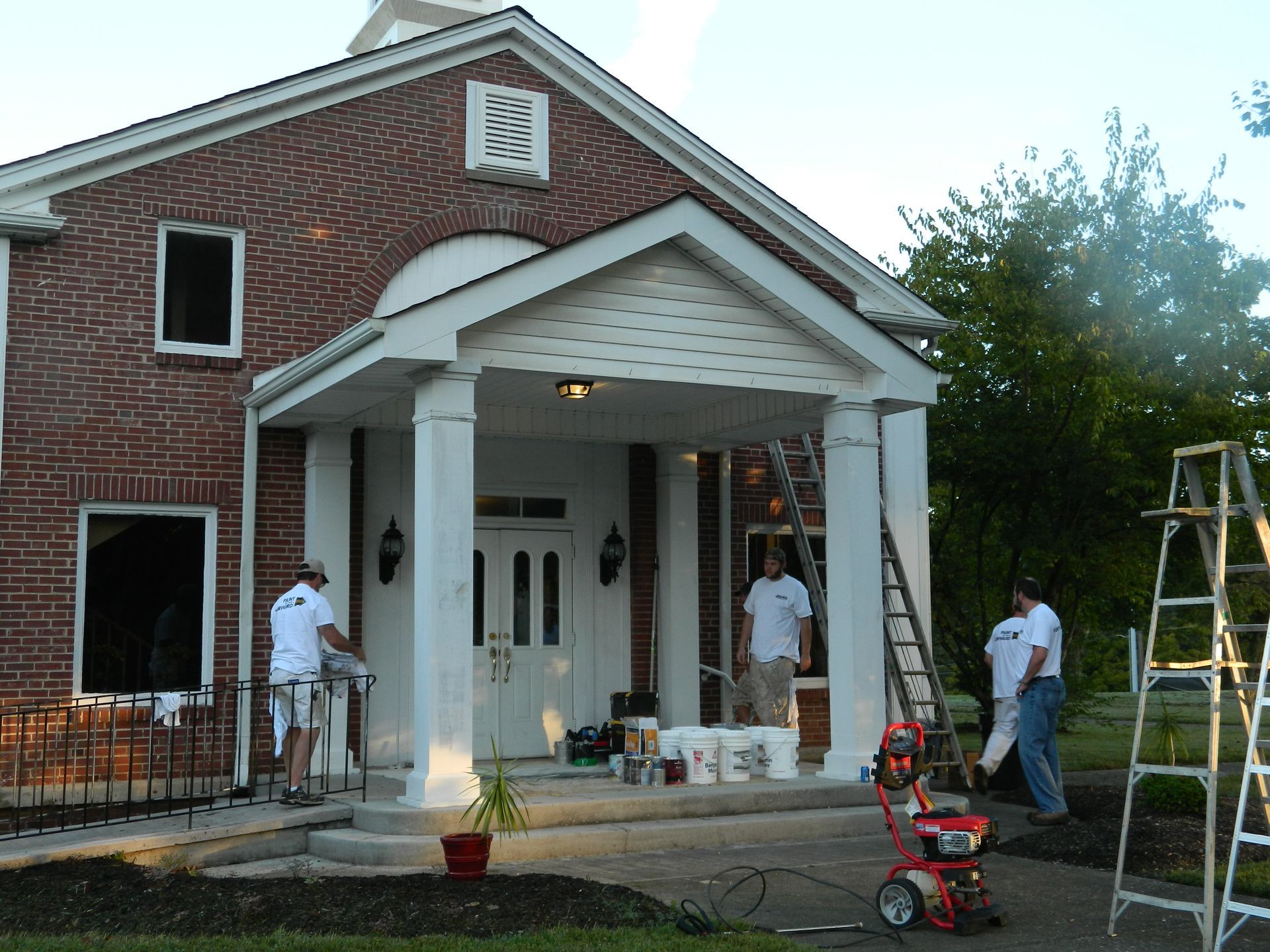 A group of people are painting a brick house