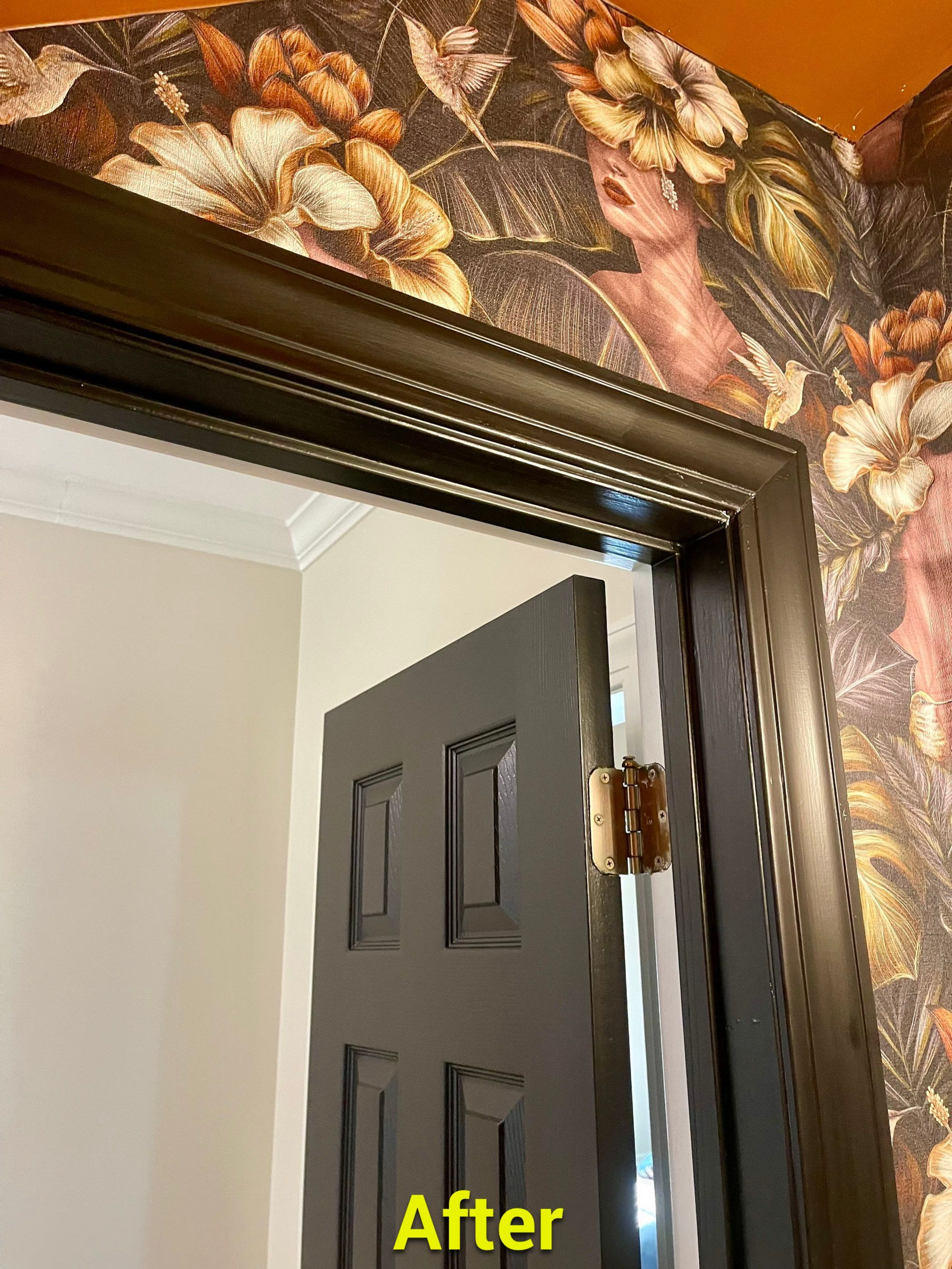 A door with a picture frame on it and a floral wallpaper on the wall.