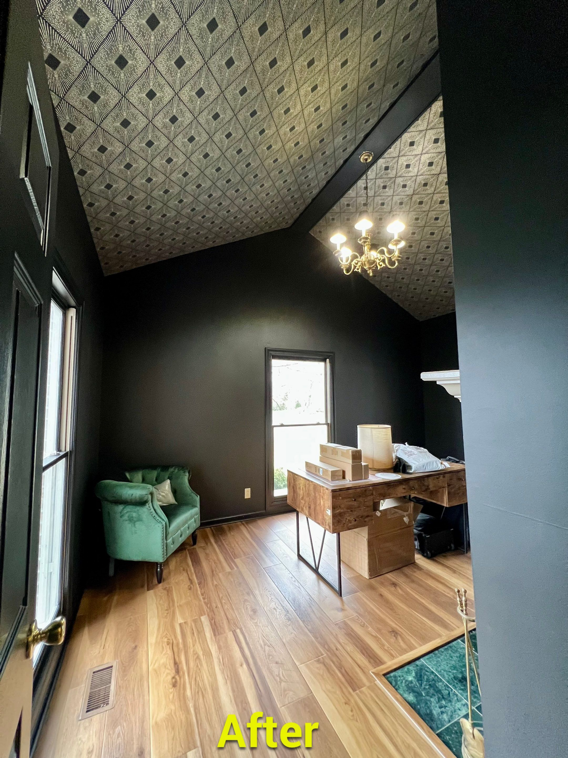A living room with black walls and a green chair and boxes on the floor.
