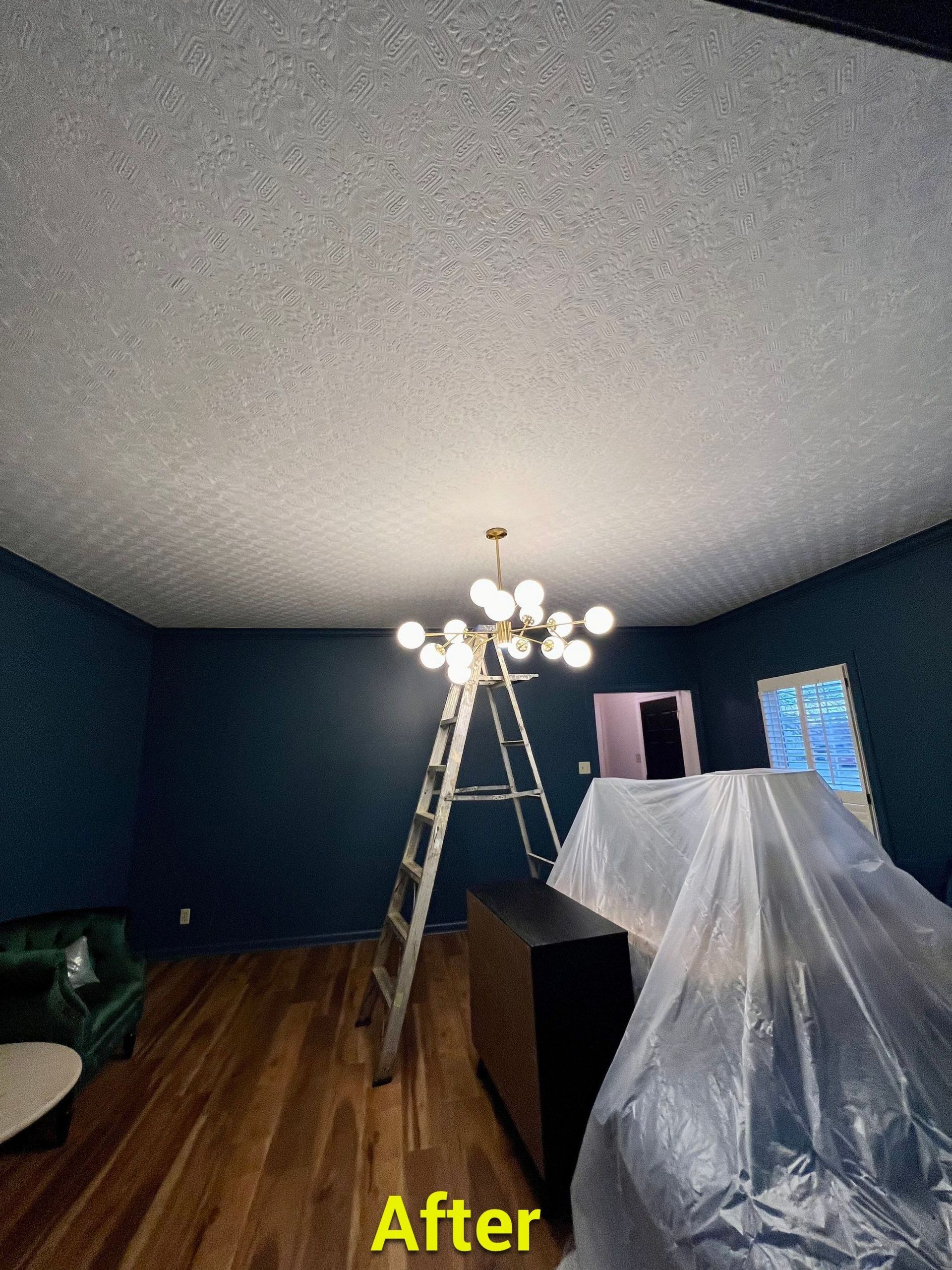A living room with a ladder and a chandelier hanging from the ceiling.