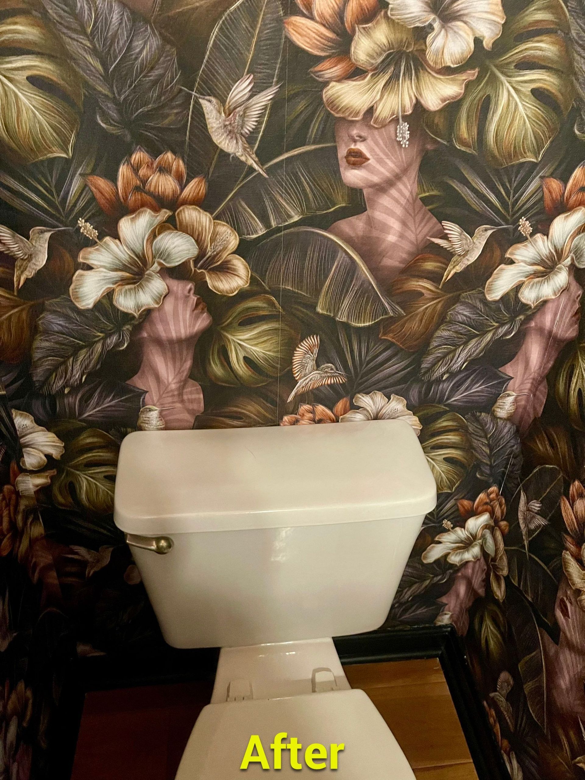 A toilet in a bathroom with a floral wallpaper on the wall.