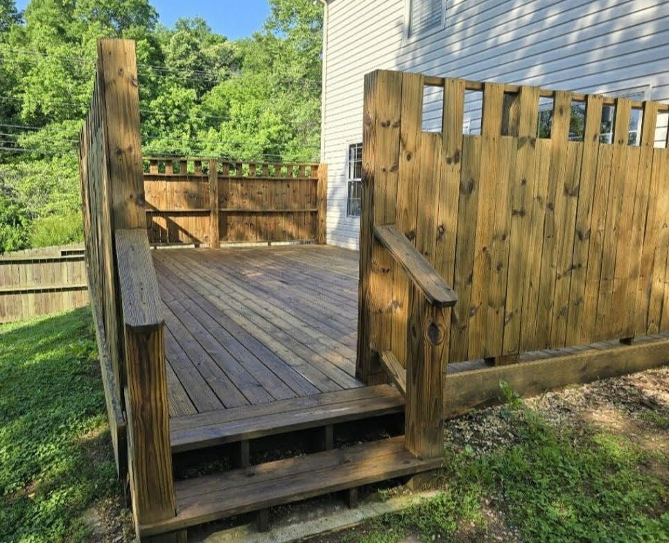 A wooden deck with a wooden fence in front of a house.