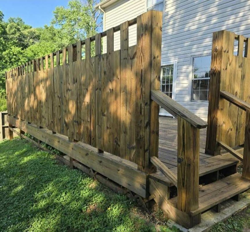 A wooden deck with stairs and a wooden fence in front of a house.