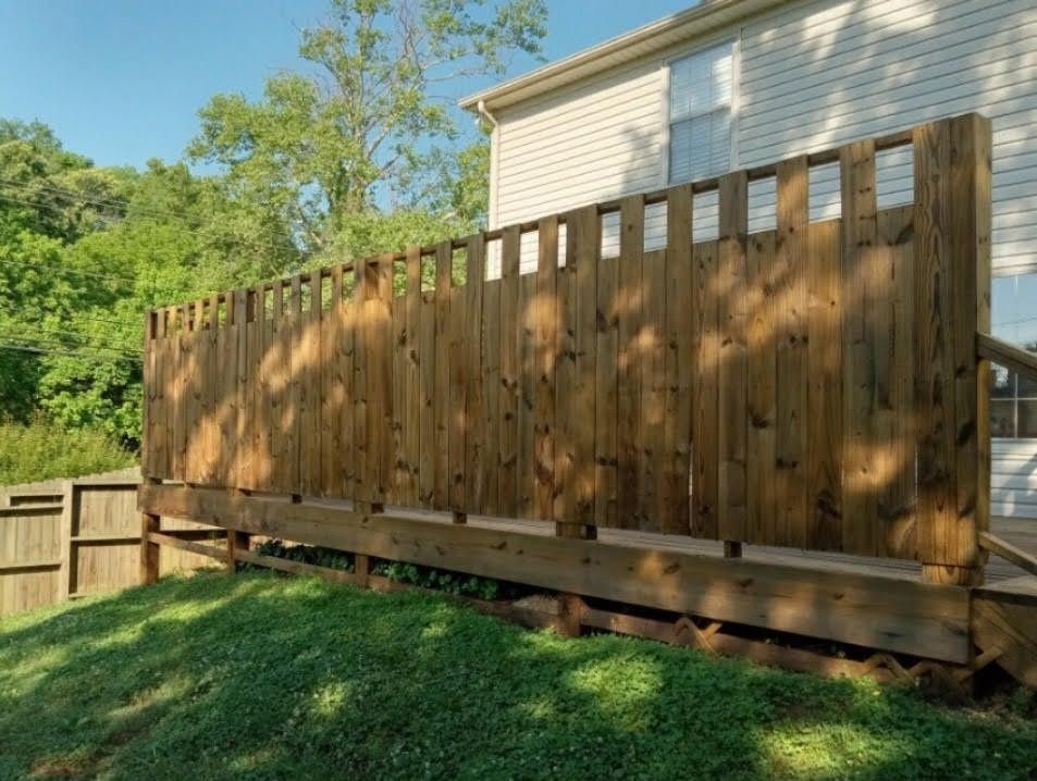 A wooden deck with a fence in front of a house.