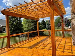 A wooden deck with a pergola on top of it.