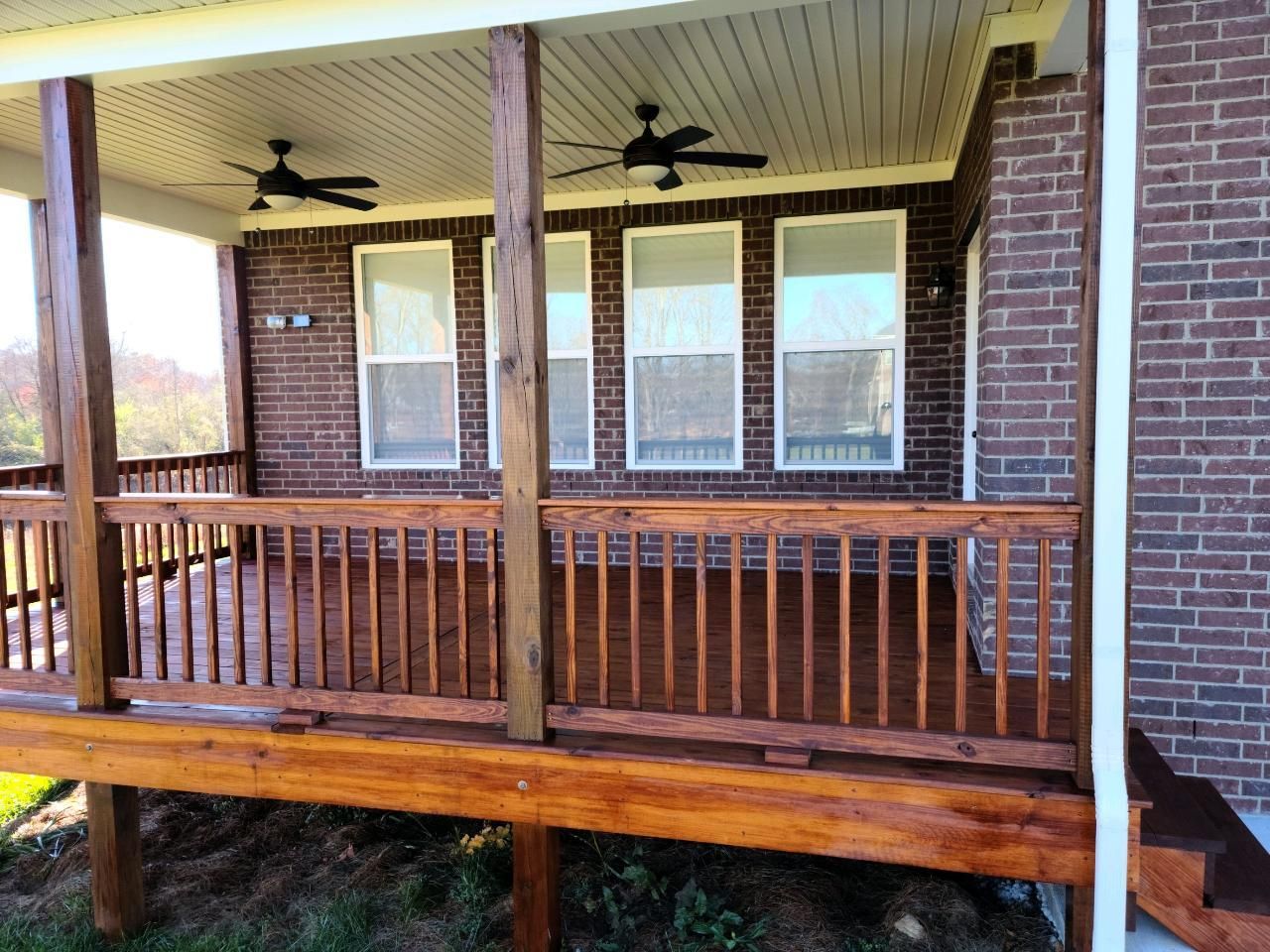 A brick house with a wooden deck and a ceiling fan.