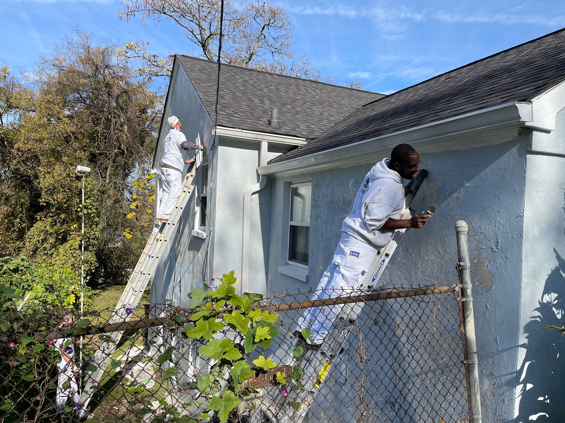 Two men are painting the side of a house.