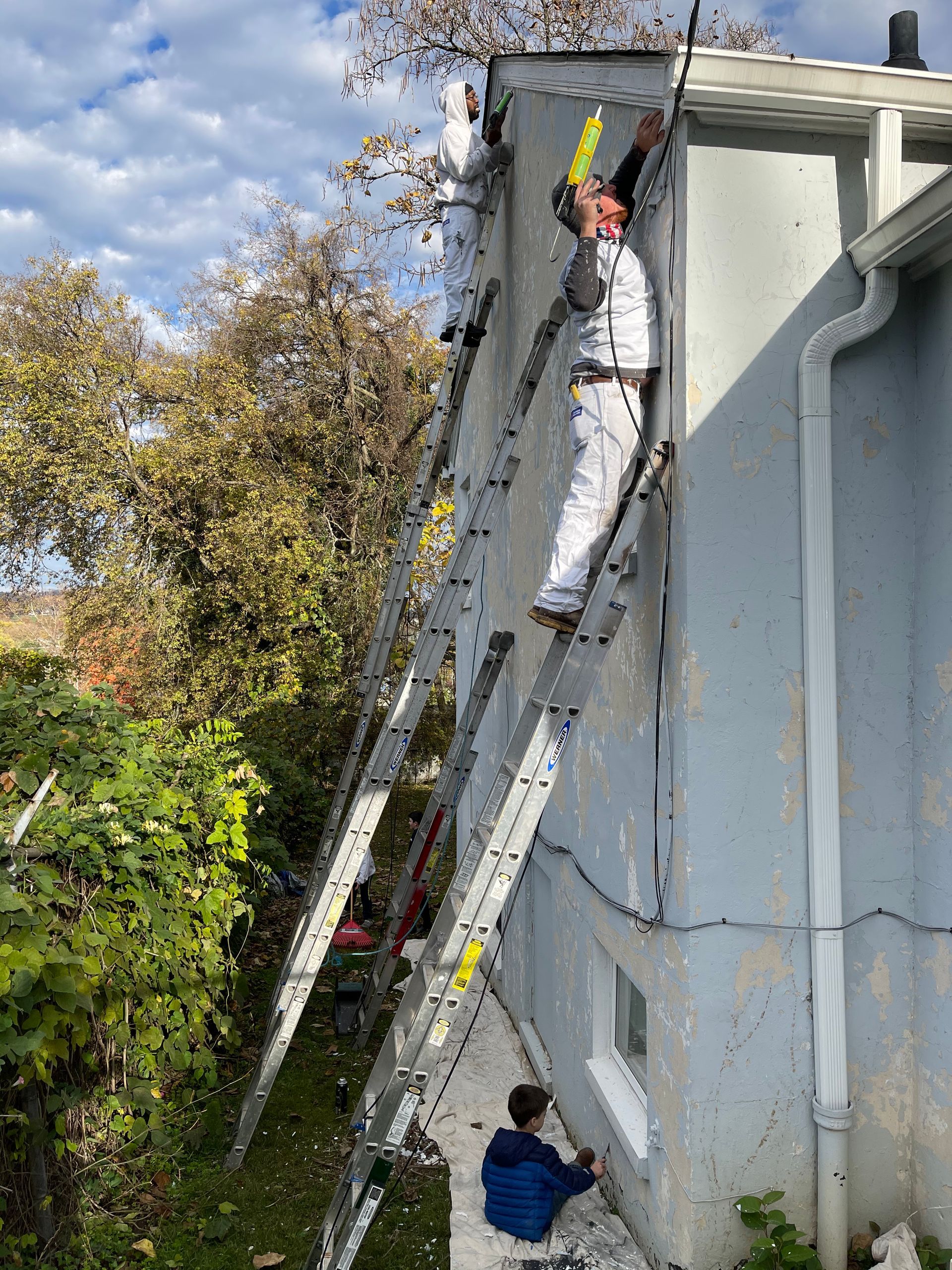 A man is standing on a ladder on the side of a building.