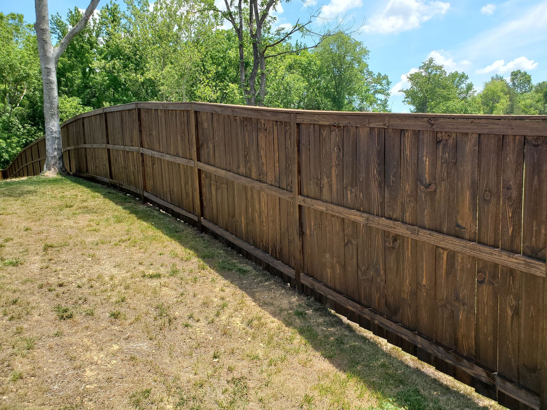 A wooden fence is sitting on top of a lush green field.