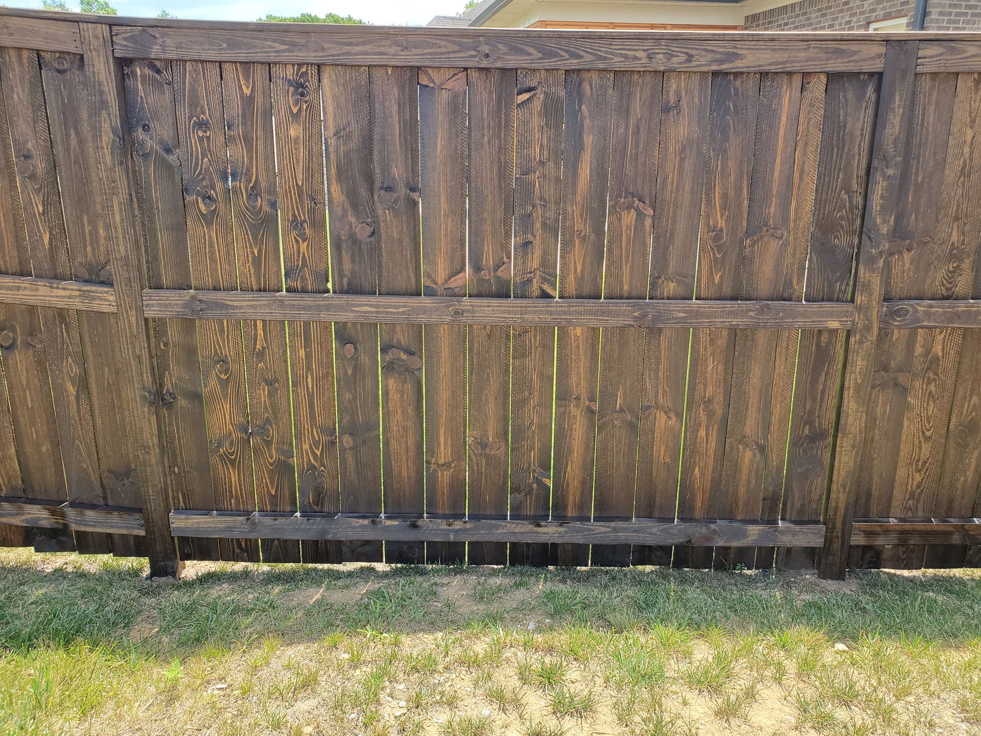 A wooden fence is sitting in the grass in front of a house.