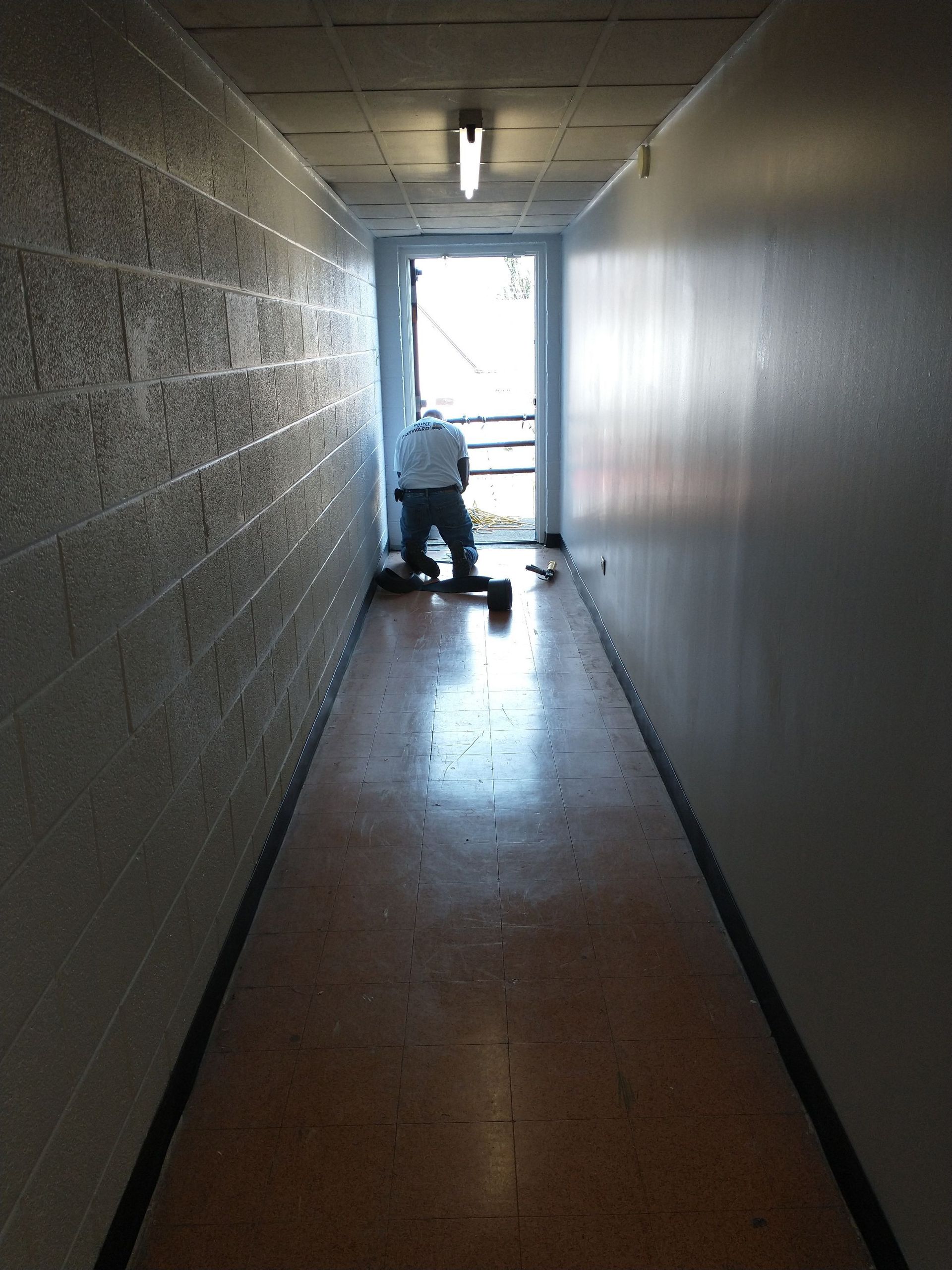 A man is cleaning a hallway with a vacuum cleaner