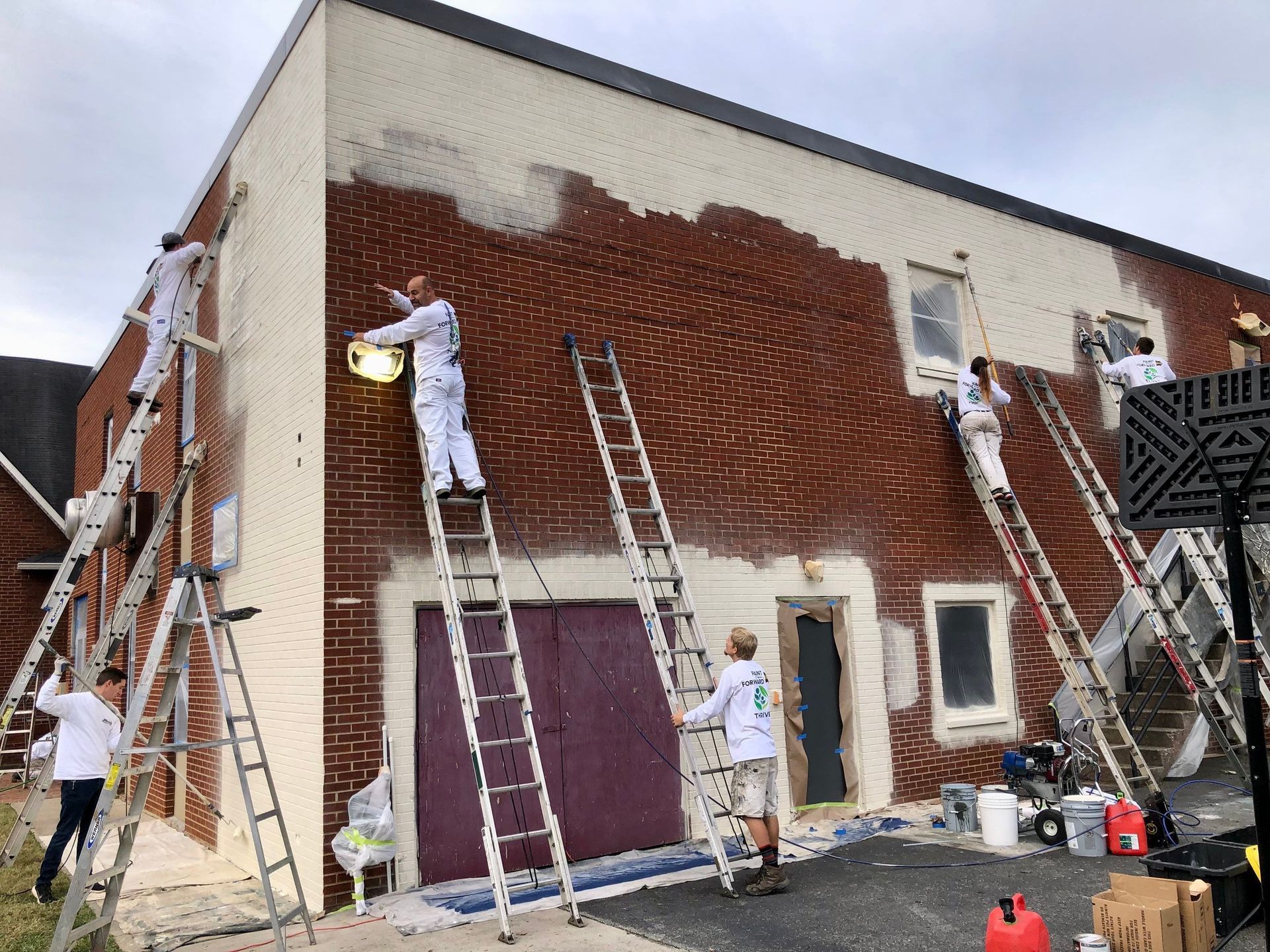 A group of people are painting a brick building.
