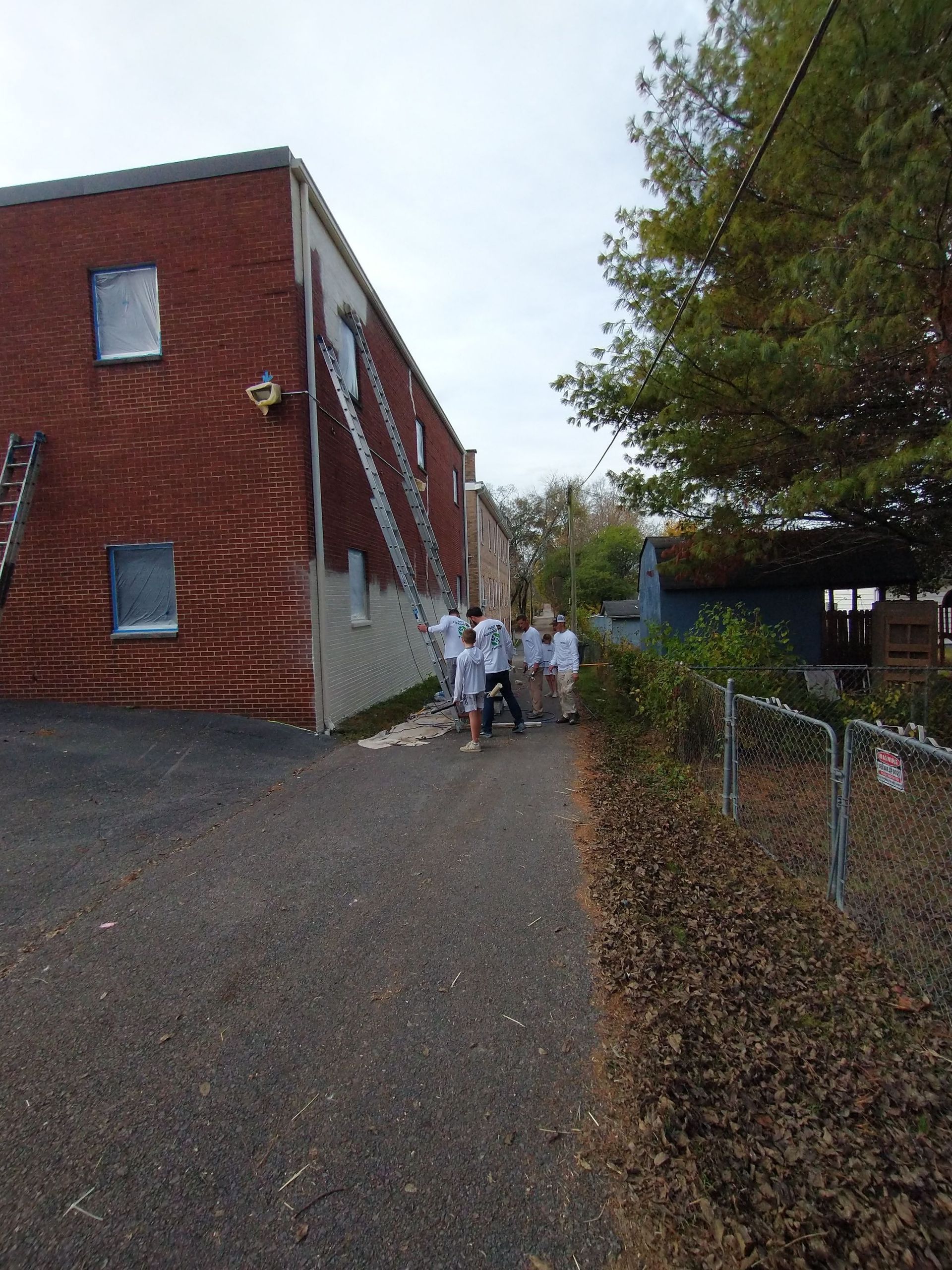A group of people are walking down a sidewalk in front of a brick building