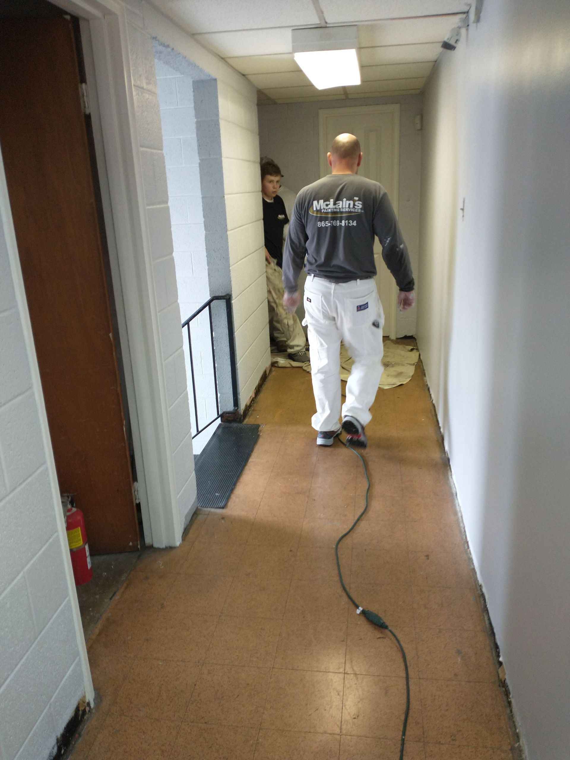 A man in a black shirt with the number 71 on the back is walking down a hallway.