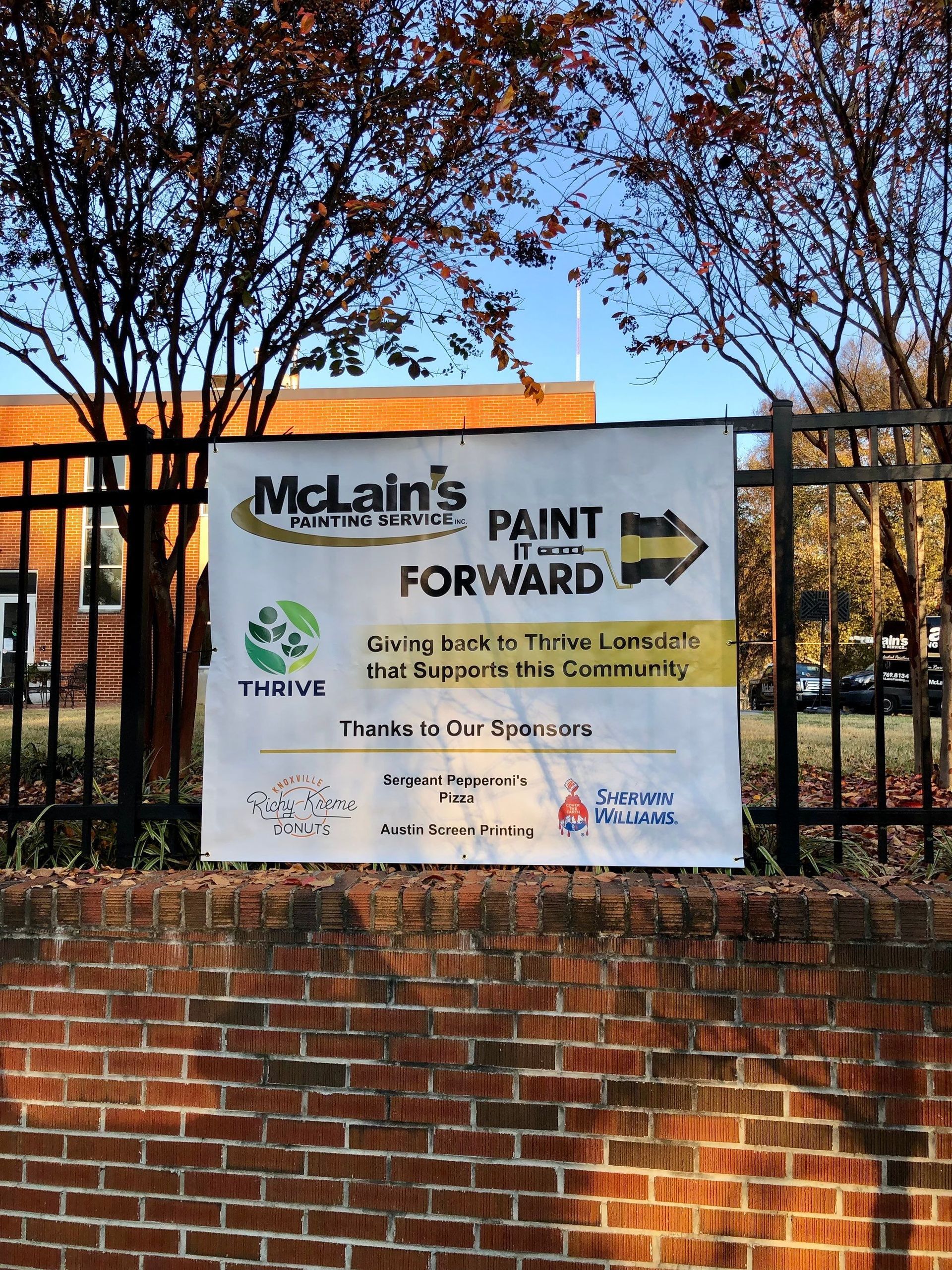 A sign for mclain 's paint forward hangs on a brick wall