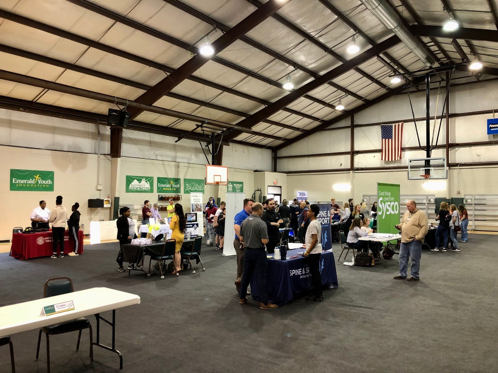 A group of people are standing around tables in a large room.