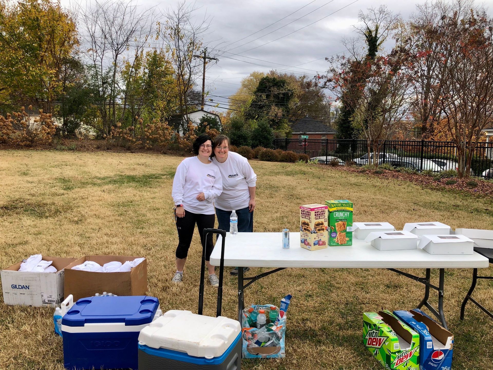 Two women are standing next to a table in a field.