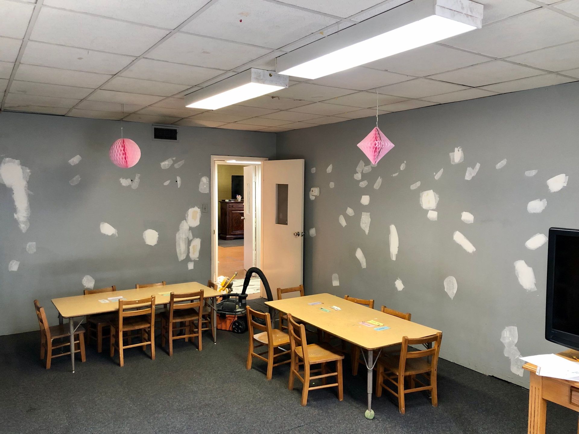 A room with tables and chairs and a vacuum cleaner in it