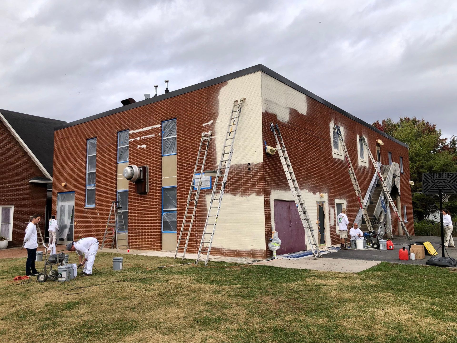 A group of people are painting a brick building.