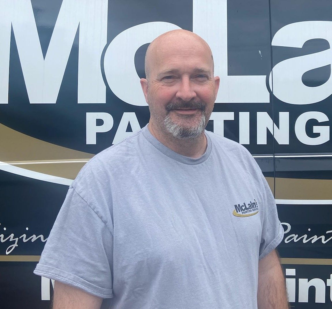 A man is standing in front of a mcla painting van