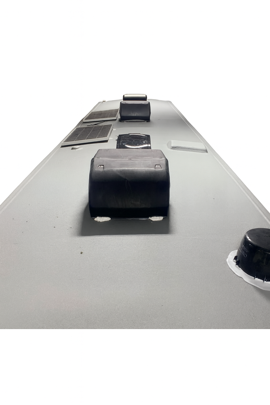 Flat, gray roof with several black vents and some damaged sections, viewed from above.