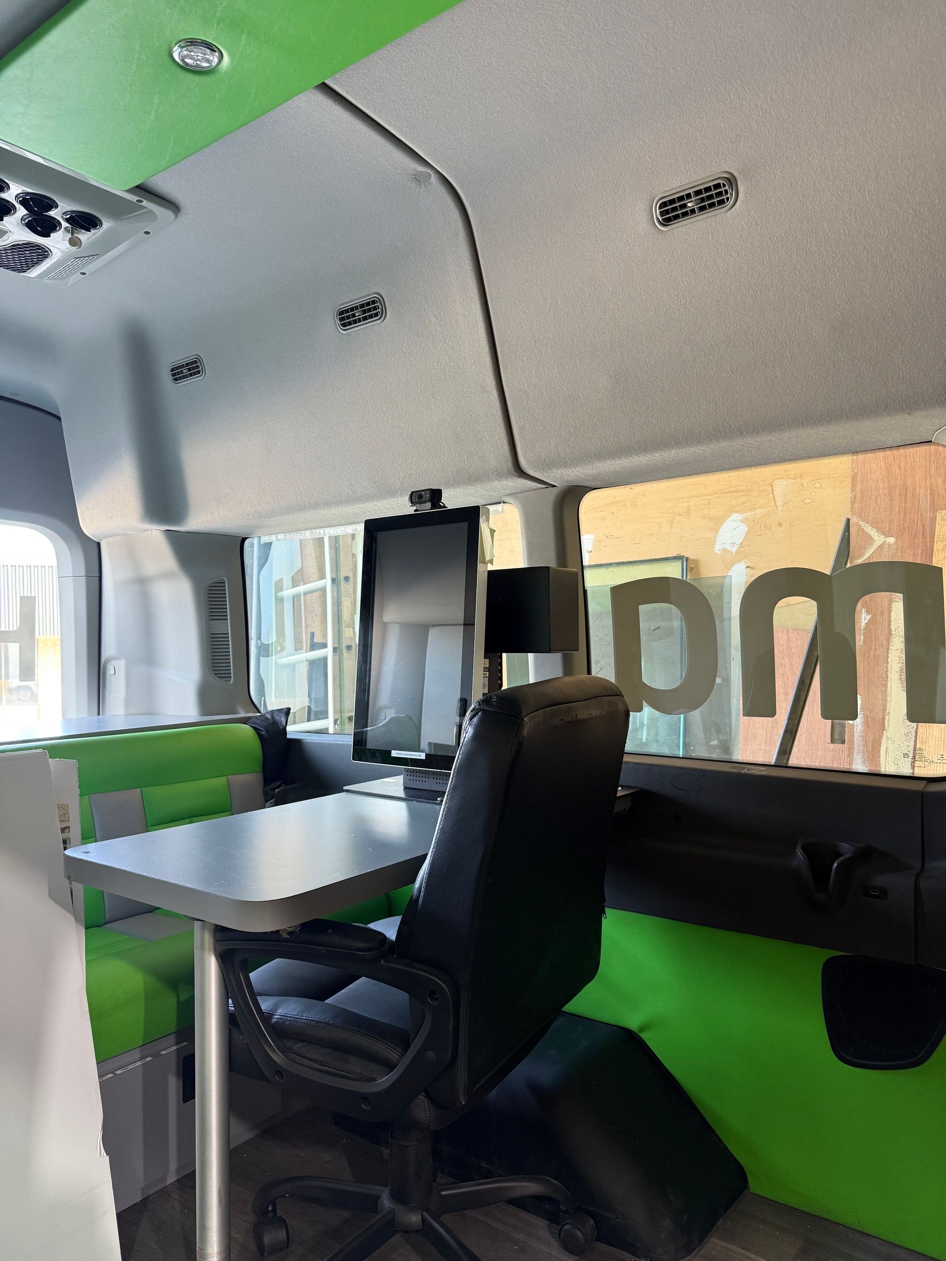 A green and white van with a desk and chairs
