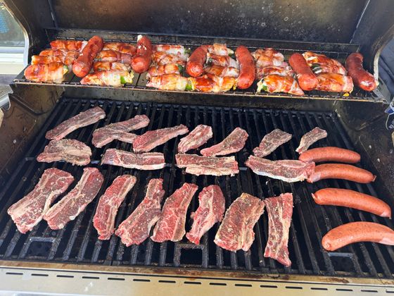 A grill with a lot of meat and sausages on it