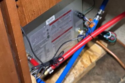 A box with wires coming out of it is sitting on a wooden table next to a pipe.