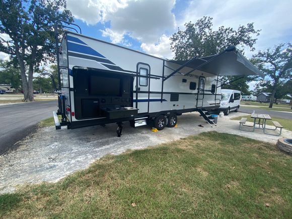 A rv is parked in a grassy area next to a picnic table.