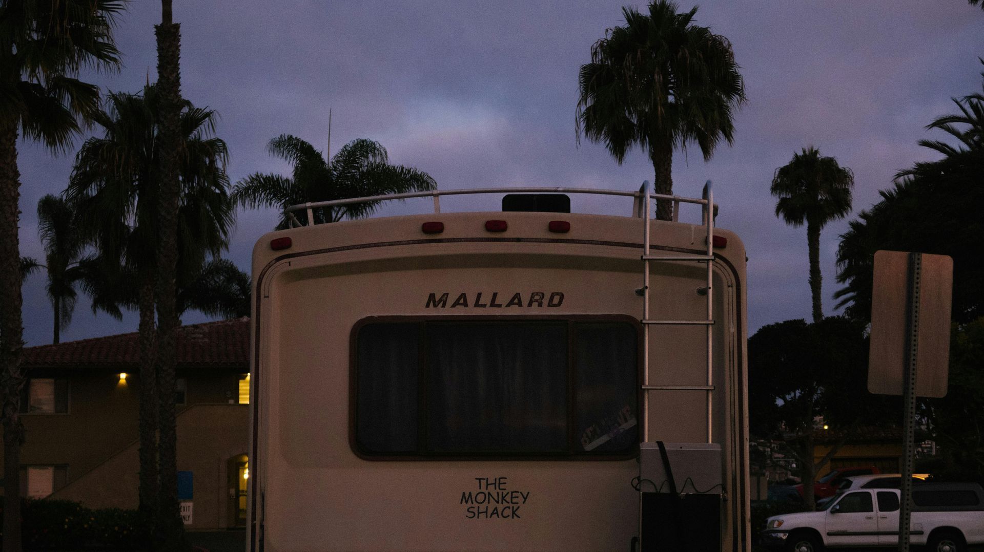 A rv parked in front of palm trees and a building