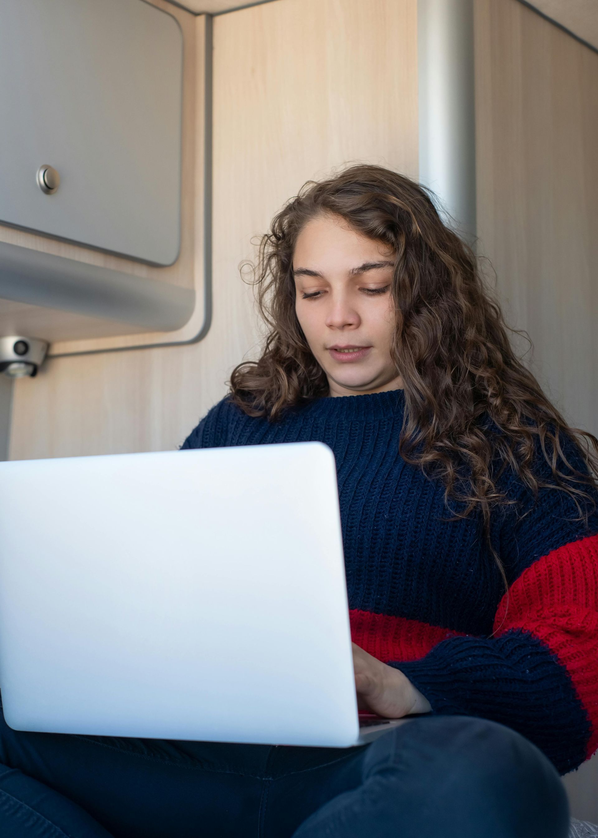 A woman is sitting on the floor using a laptop computer.