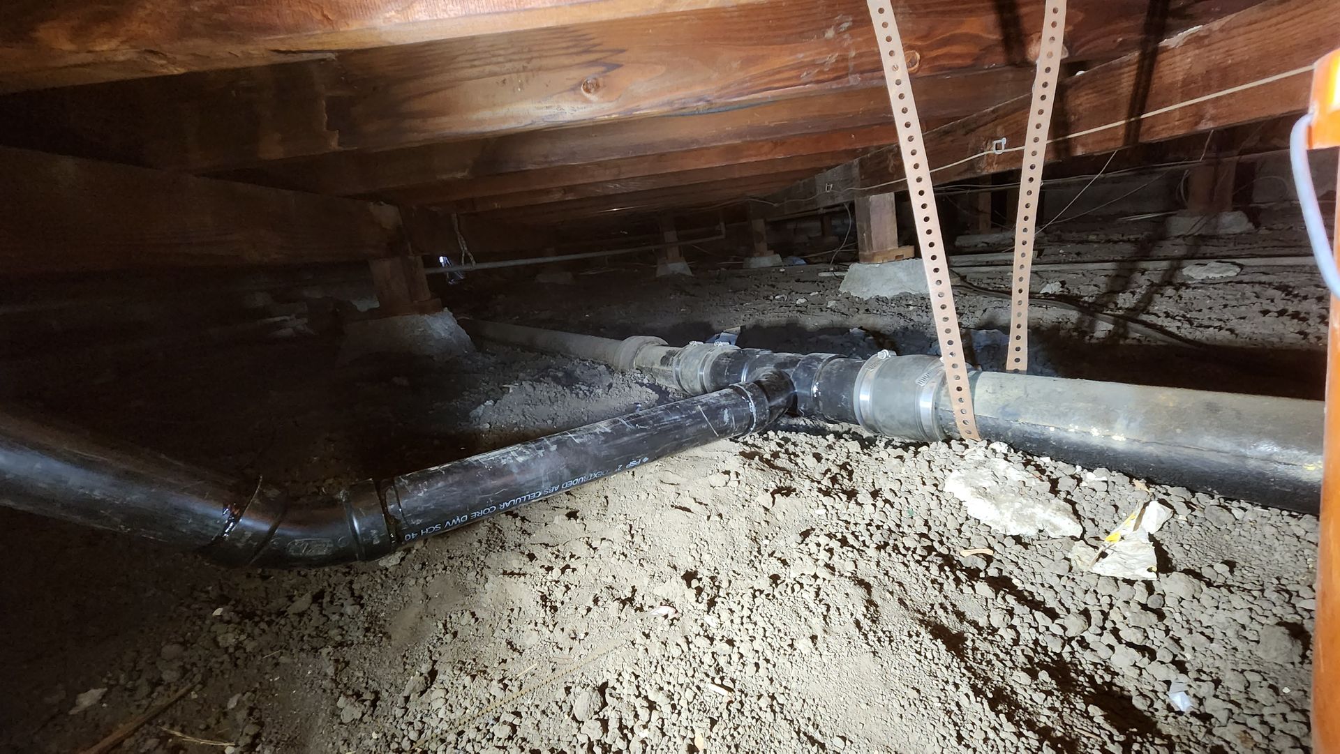 A bunch of pipes are hanging from the ceiling of a house.