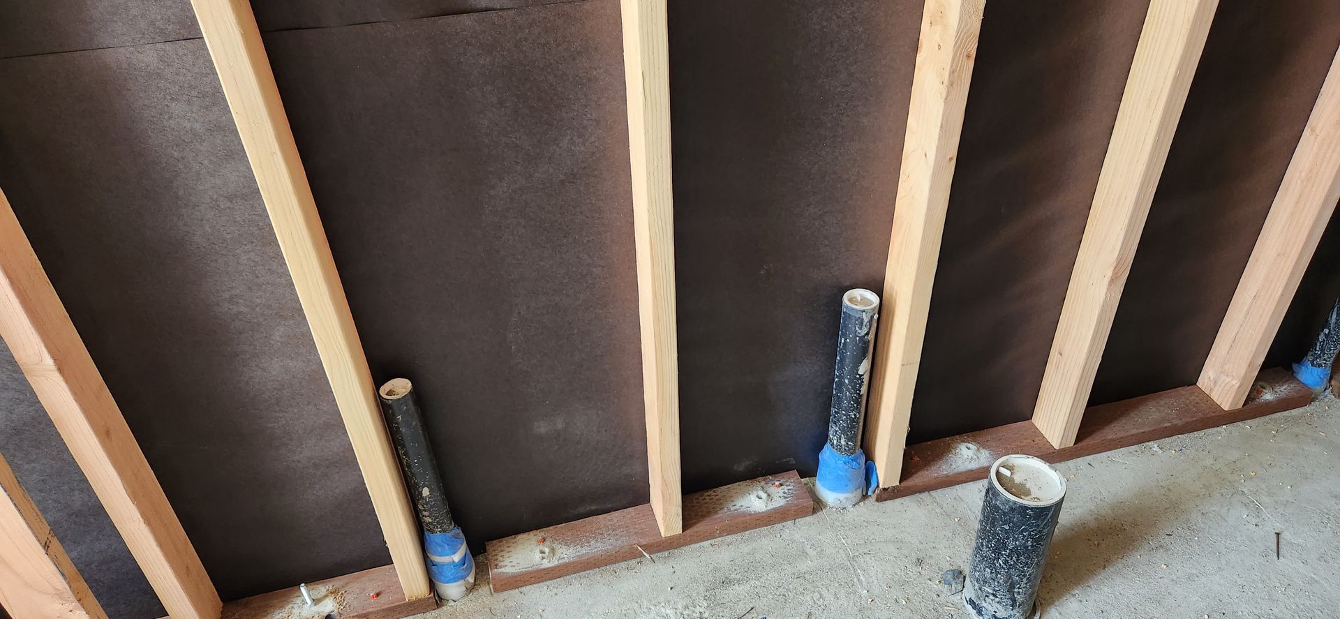 A wooden wall with pipes attached to it is being built.