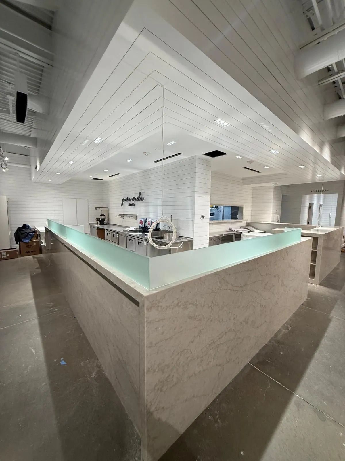 Interior of a modern bar with a light-colored countertop and ceiling. Construction in progress.